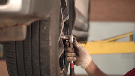 Asian man car mechanic replacing a car tire in garage workshop. . Auto service, Car-care center removes the wheel, Repair and maintenance of the car in service.の写真素材