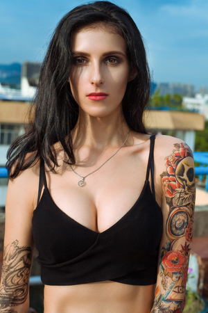 strong dark hair tattooed model looking straight to the cameraの写真素材