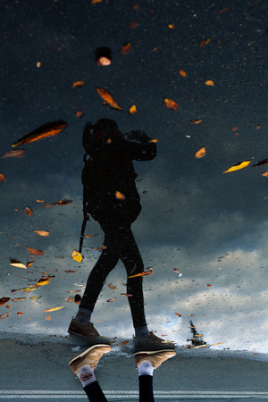 black silhouette of skinny girl travels and drinks on the road in autumnの写真素材