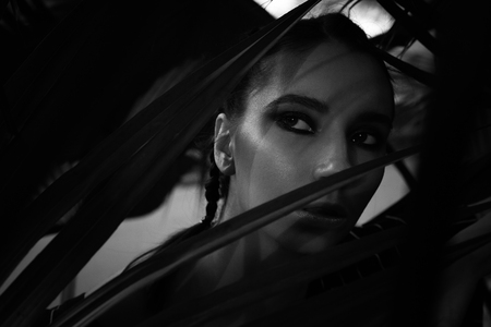 dark hair girl looking scared from the bushes in black and whiteの写真素材