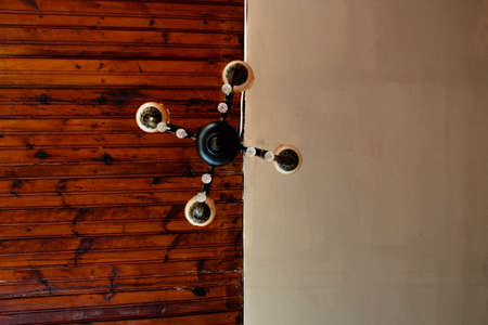 A ceiling lamp is centered in the photo with wooden and white ceiling.