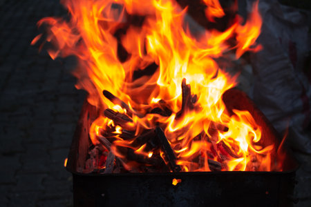 Stacked wooden pieces in a grill burning in orange fire. Preparation for the grill at night. Dinner...