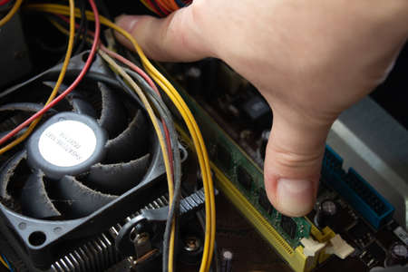Man hand pushing a ram into its socket to make the computer work again with normal functions.