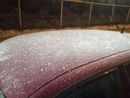 Top of a red car frozen by extremely cold weather.