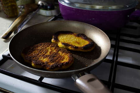 Man hand cooking chicken schnitzel in a granite pan on blue fire.