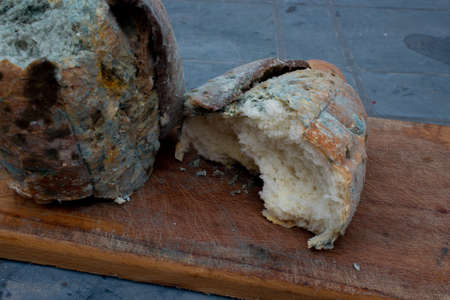 Mouldy bread on a wooden cutting board. Selective focusの写真素材
