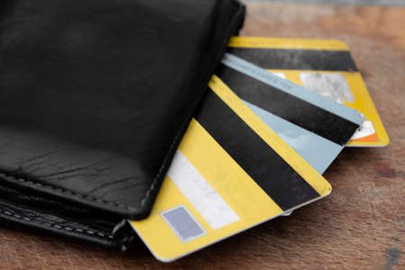 A black leather wallet with some bitcoins, coins and credit cards comin out from it. Economical...