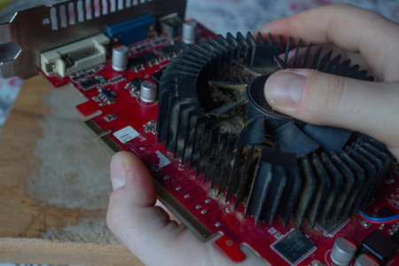 Man hand with a dirty toothbrush cleaning a rusty and old graphic card on a wooden cutting board....