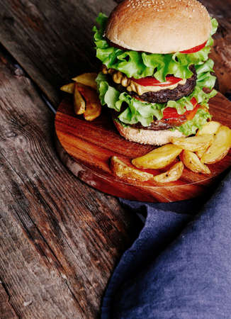 Close up of a hamburger with side dishes on a plate.の写真素材