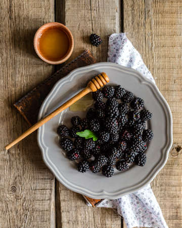 Overhead view of blackberries and honey in a ceramic plateの写真素材