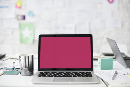 A laptop along with a steel mug on the table