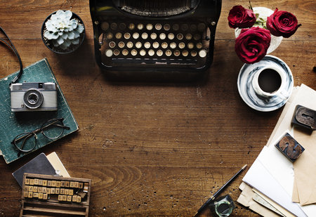 Flat lay of a vintage typewriter and camera on a weathered wooden tabletopの写真素材