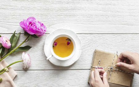 Overhead view of a cup of herbal tea alongside a stack of envelopes being tied up
