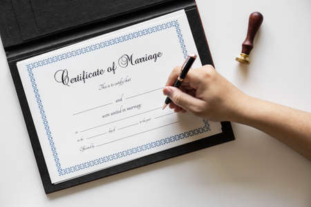 Overhead view of a hand writing on the Certificate of Marriage