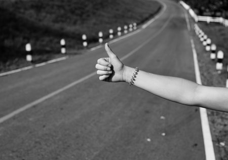 A womans hand with thumbs up gesture asking permission for a lift