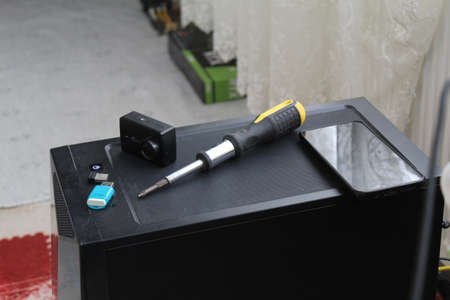 A USB memory stick, screwdriver and an action camera on a computer case. Black concept