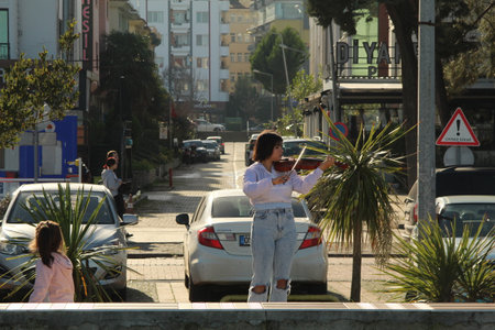 Samsun,Turkey - November 27, 2022 A woman playing violin at the beach and collecting money. high...