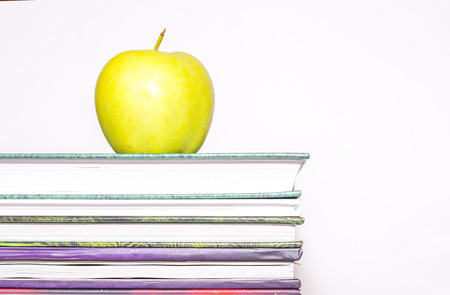 Green apple on a stack of books on white backgroundの写真素材