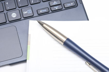 Notepad and pen on keyboard on white backgroundの写真素材