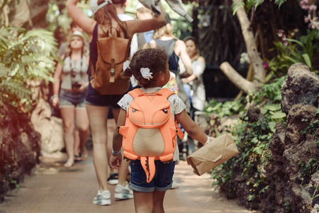 Portrait of little mixed-race girl smiling happily, background of green bamboo trees. Concept: vacation, summer time, children, daughter, tropical forest, travel, baby, kids, childhoodの写真素材