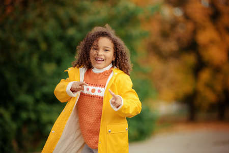 Portrait of cute adorable little girl child making funny silly faces, showing tongue, in autumn fall...