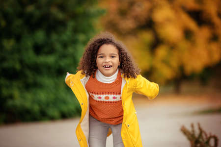 Portrait of cute adorable little girl child making funny silly faces, showing tongue, in autumn fall park outside, playing having fun, lifestyle childhoodの写真素材