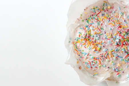 Easter cake, sweet bread decorated with white glaze and colored meringue. Kulich wrapped in a craft paper on the white background.の写真素材