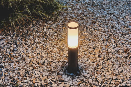 A night lamp in the garden illuminates the summer cottage. Summer weather