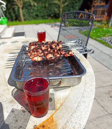 Skewers of grilled meat resting on a table with refreshing beverages in a sunny backyard during a summer gatheringの写真素材