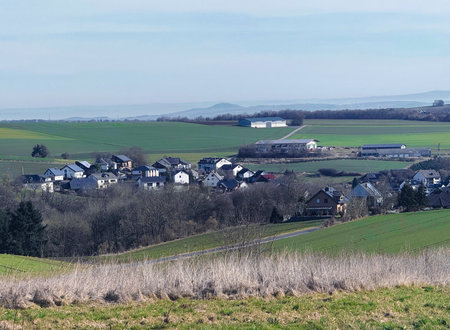 Wind turbines for renewable electricity, village houses and yellow rapeseed field