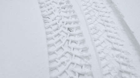 Wheel tracks on the winter road covered with fresh wet snow. Poor driving conditions in winter. Background texture with tyre wheels trails on slippery snow ground.の写真素材