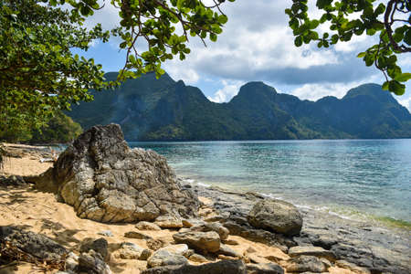 Beautiful beach landscape with rocks in foreground and ocean, mountains in background of Helicopter...
