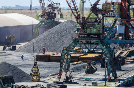 Crane in river port. Heavy cranes unloading metal to import. Steel delivery.
