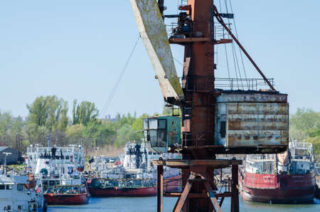 Crane in river port. Heavy cranes unloading metal to import. Steel delivery.の写真素材