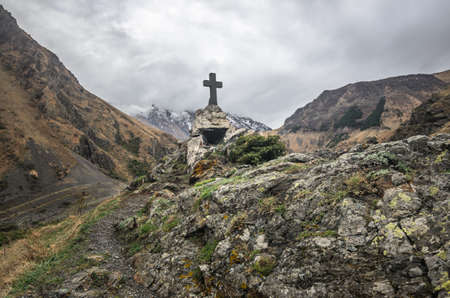 Path to ancient medieval monument in mountains of Caucasus. Christian cross in touristic place.の写真素材