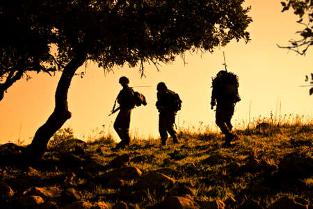 Three army soldiers patrolling during sunsetの写真素材
