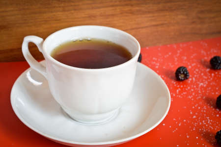 tea cup on a red table with sugar and blackberriesの写真素材