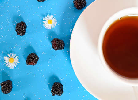 tea cup on blue table with flower and blackberriesの写真素材