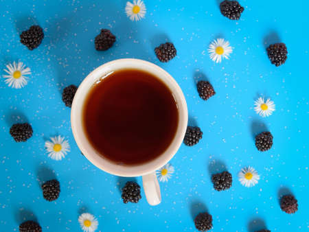 tea cup on blue table with flower and blackberriesの写真素材