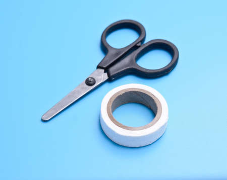 medical adhesive tape and scissors on blue background