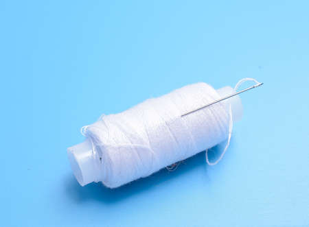 white threads and a needle on a blue backgroundの写真素材