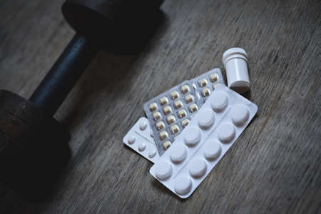 the old dumbbell on a wooden background with anabolic, dirty sport abstract and conceptの写真素材