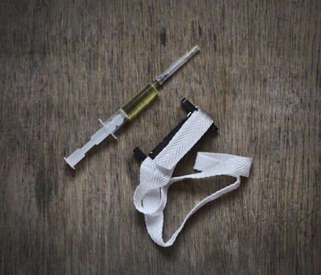accessories addict - tourniquet, syringe, a drug on the wooden background, drugs kill abstractの写真素材