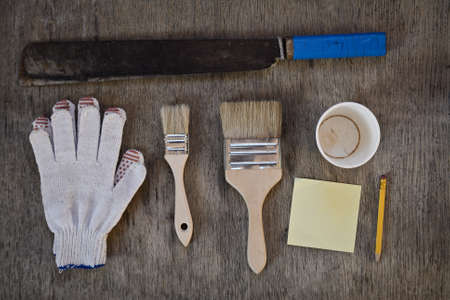machete. gloves and two brushes to paint, to write notes with a simple pencil and a blank for the cup of coffee. hard work abstractの写真素材