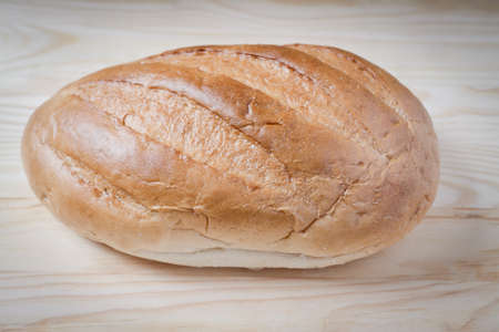 Large loaf of bread isolated on wooden tableの写真素材