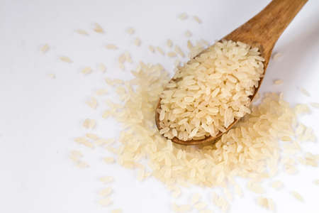 The arborio rice in wooden spoon isolated on white backgroundの写真素材