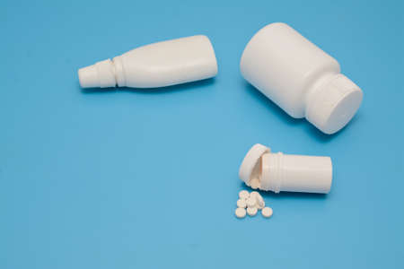 Pills and white bottles of medicine on a blue background.の写真素材