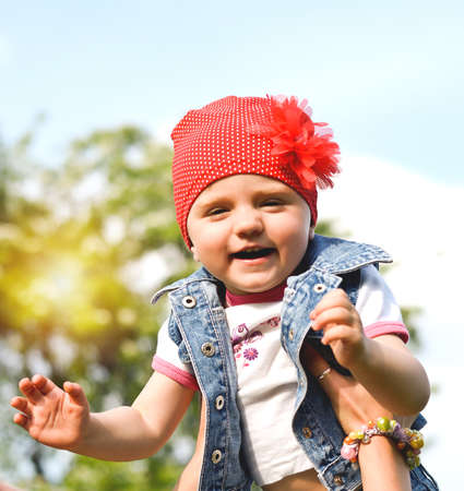 Little girl two years in the hands of her mother against the blue sky in the park. Baby portraitの写真素材