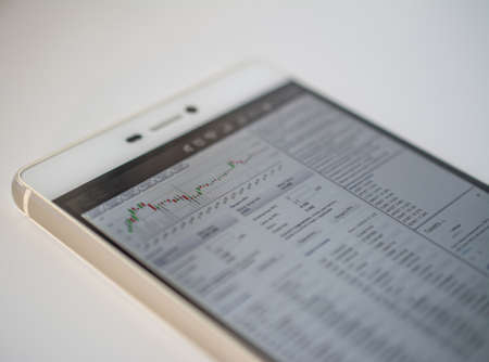 smart phone on table Graphs of financial markets for the growth of bitcoin and other crypto-currenciesの写真素材