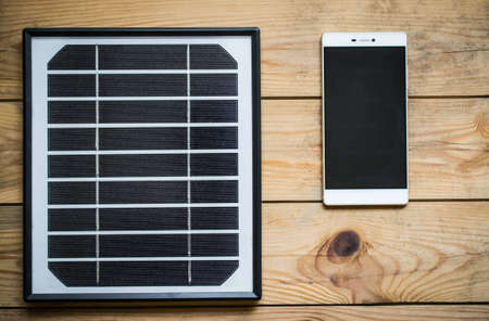solar panel and smartphone on the wooden tableの写真素材